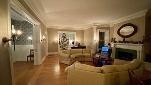 A living room with a fireplace, a Christmas tree, and a laptop on a table. - Beautiful, large, historic 6 bedroom home.   (Oswego)