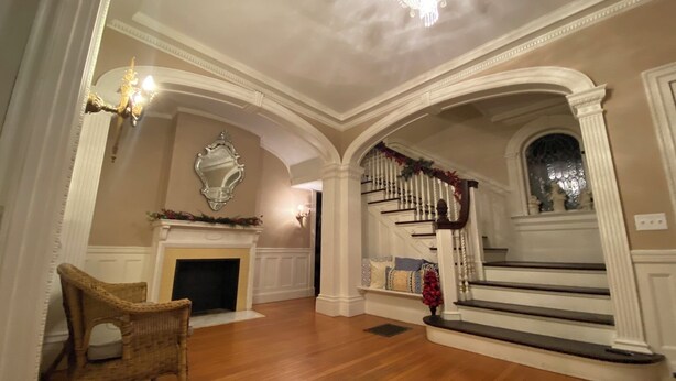 A grand foyer with a fireplace, a staircase, and a chandelier. - Beautiful, large, historic 6 bedroom home.   (Oswego)