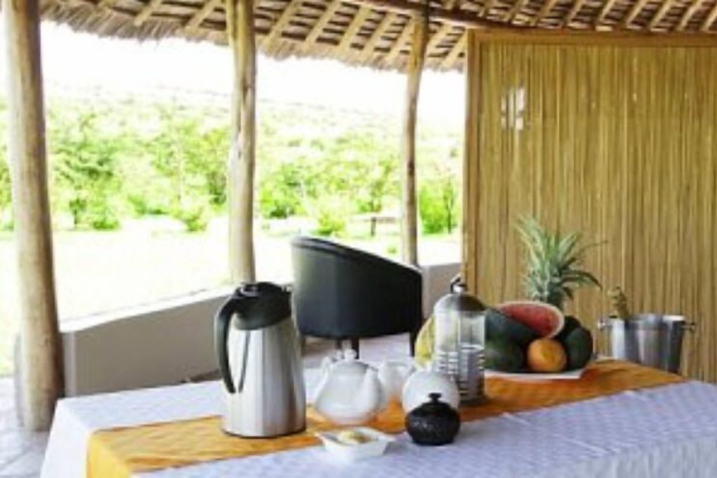 A breakfast setup with a table, a kettle, a fruit bowl, and a coffee pot.