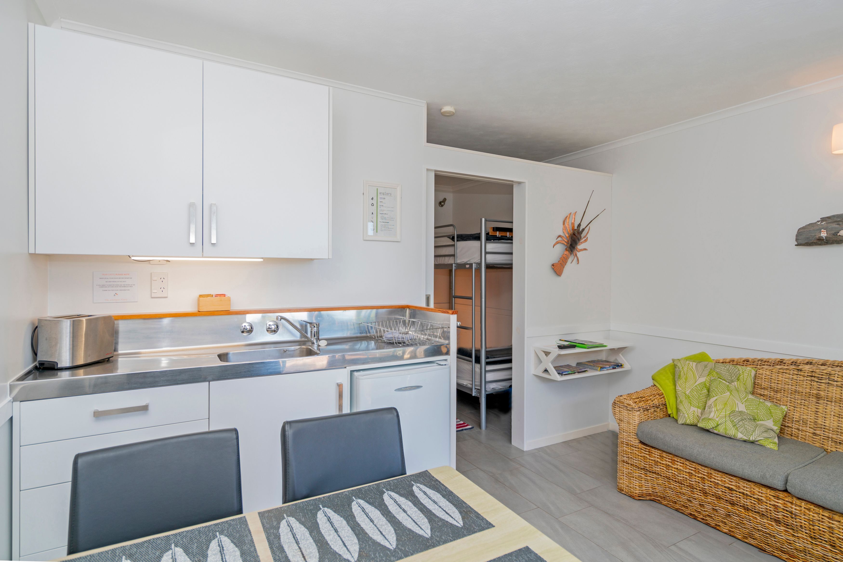 Una cocina compacta con armarios blancos, un lavamanos empotrado y una zona de comedor con mesa y sillas.