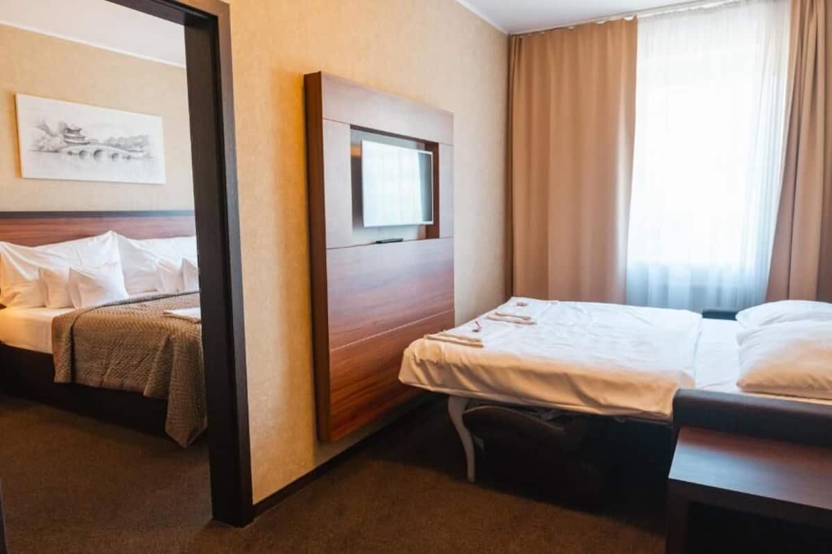 Ein Hotelzimmer mit Bett, Nachttisch, Fernseher und einem Fenster mit Vorhängen.