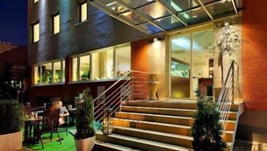 Un hôtel à l’extérieur moderne, doté de nombreuses fenêtres et d’un escalier menant à l’entrée.