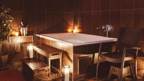 Une salle de bain moderne dotée d’une grande baignoire, de sièges en bois et d’un éclairage d’ambiance.