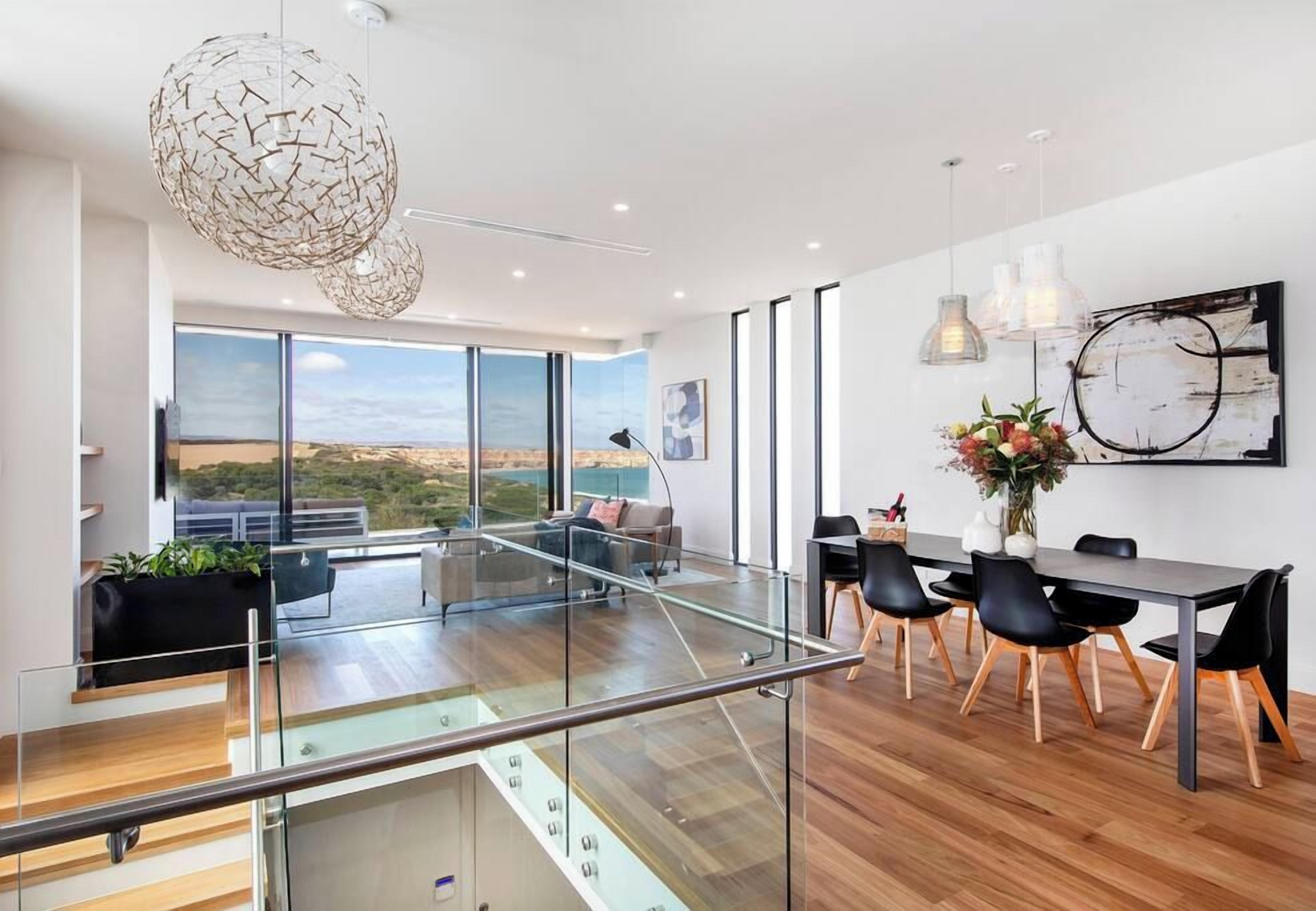 A modern interior with a dining area, large windows, and a view of the outdoors.