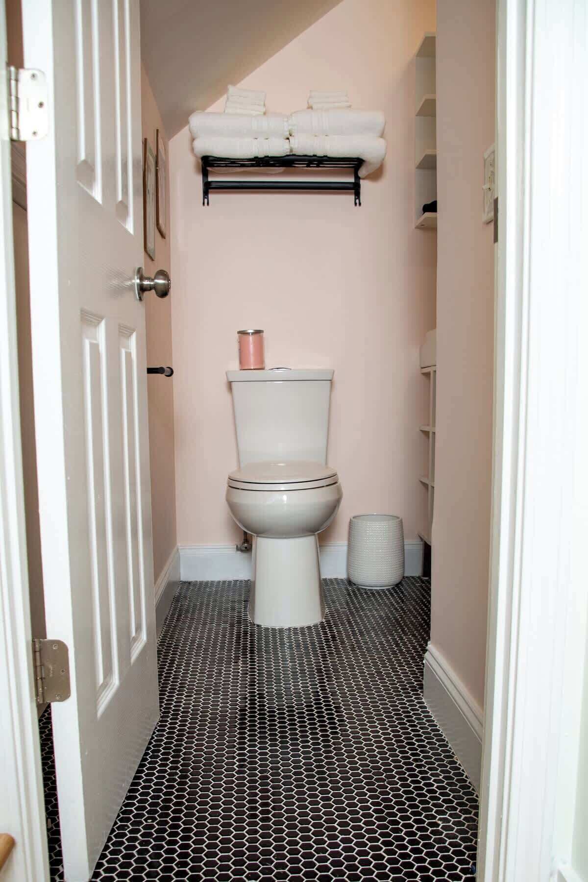 A bathroom with a toilet, a sink, a towel rack, and a shower curtain rod.