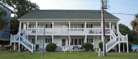 A two-story building with a porch, a sign indicating 'Compass Bend 300,' and a flagpole with an American flag.