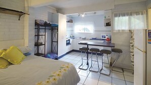 A compact room with a bed, a bunk bed, a kitchenette, and a small bar area. - Welcome to your Home away from Home. Pacific Studio offers everything to make your stay comfortable (Nambucca Heads)