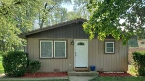 A small, single-story building with a front door, two windows, and a small porch area. - Cozy Cabin In Roselle (Roselle)