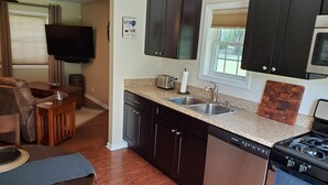 A kitchen with dark cabinets, a granite countertop, a dishwasher, and a stove. - Cozy Cabin In Roselle (Roselle)