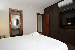 A modern hotel room with a bed, a mirror, a sink, and a TV. - OZPED Flats Particulares Bonaparte (Brasília)