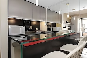 Eine moderne Küche mit einer Glasinsel, weißen Barhocker und einer Uhr an der Wand.