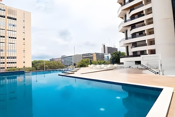 Ein Pool mit Holzterrasse, umgeben von modernen Gebäuden.