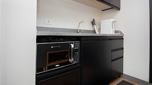 A compact kitchen with a built-in oven, a coffee maker, and a microwave. - OZPED Flats Particulares Bonaparte (Brasília)