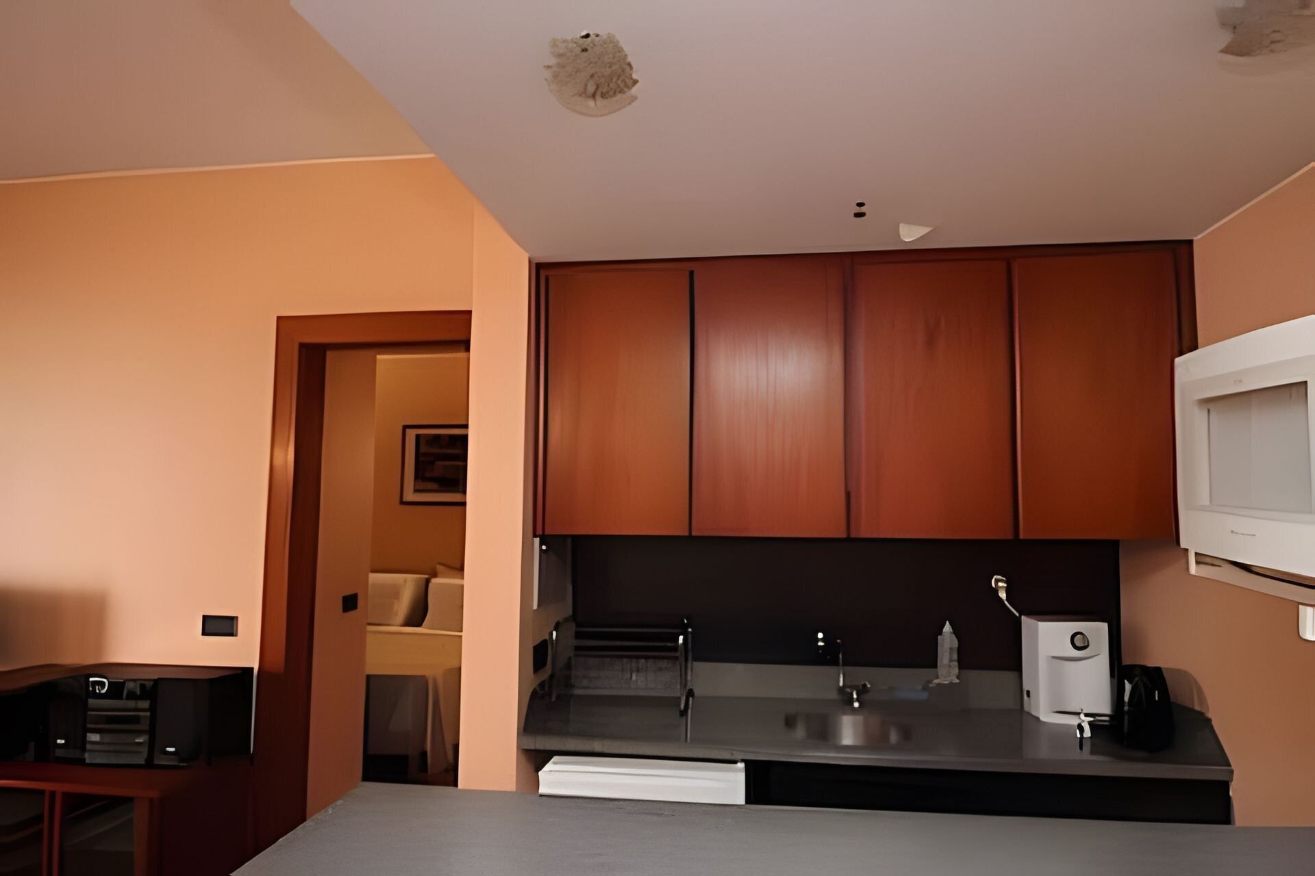 Una cocina con armarios de madera, microondas, lavamanos y encimera.