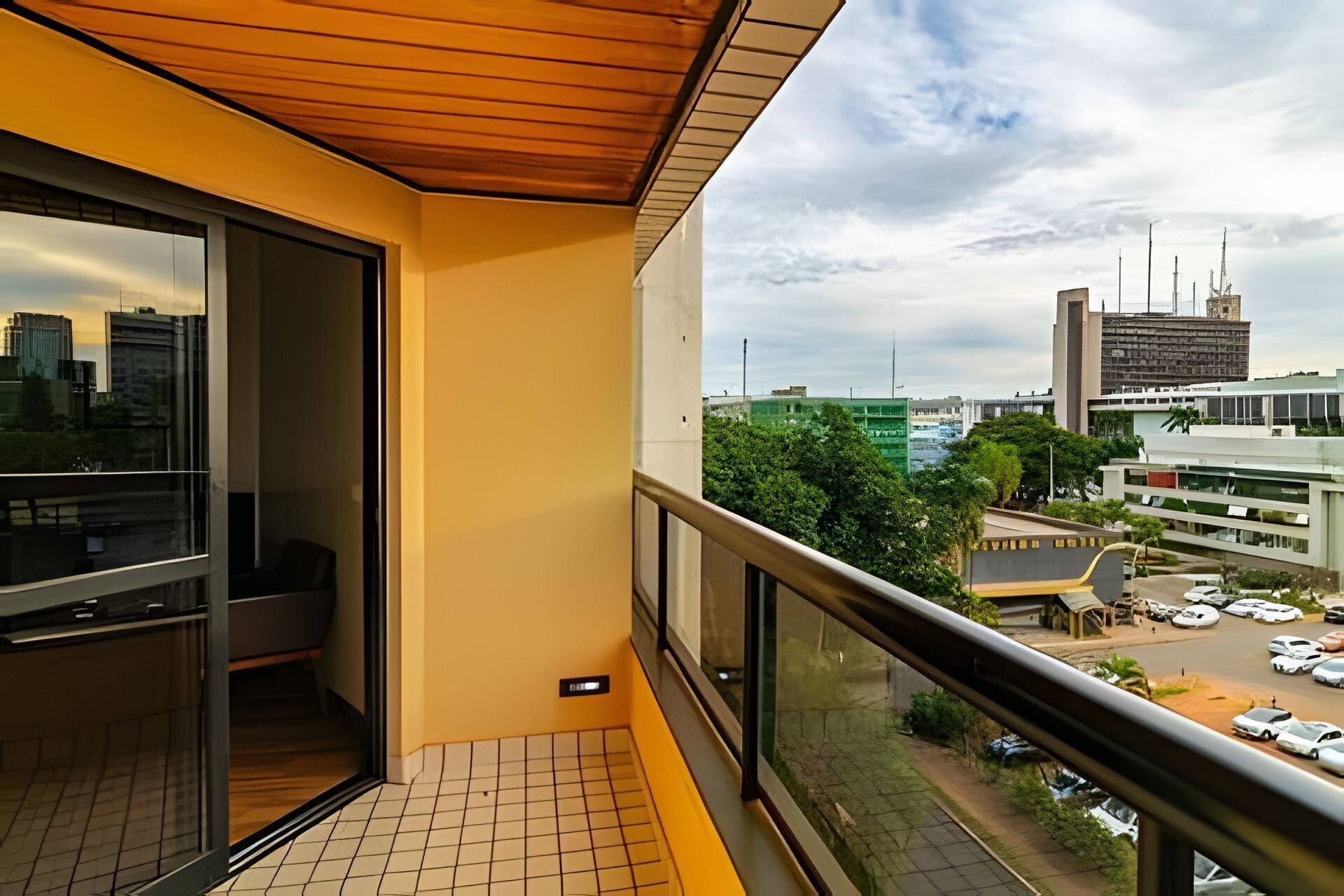 A balcony with a tiled floor, a wooden ceiling, and a city view.
