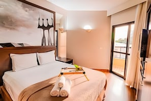 Ein Hotelzimmer mit Bett, Flachbildfernseher, Fenster mit Vorhängen und Wandlampe.
