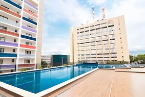 A rooftop pool with a view of a multi-story building with balconies. - OZPED Flats Particulares Bonaparte (Brasília)