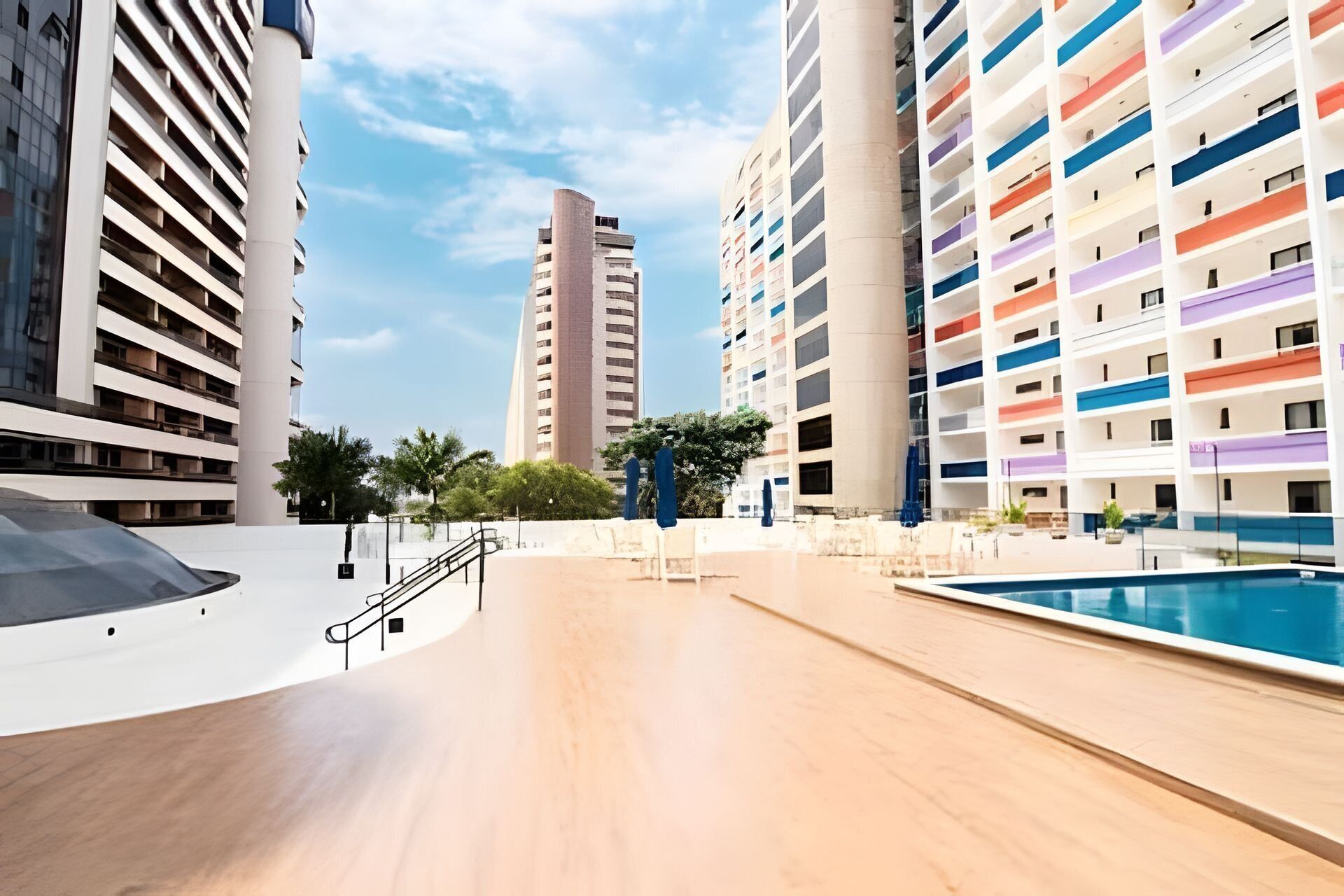 Un hotel moderno con piscina, varios pisos y una escalera central.