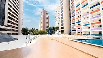 Un hotel moderno con piscina, varios pisos y una escalera central.