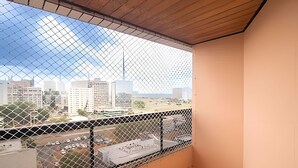 A balcony with a chain-link fence, a tiled floor, and a view of a cityscape. - OZPED Flats Particulares Bonaparte (Brasília)