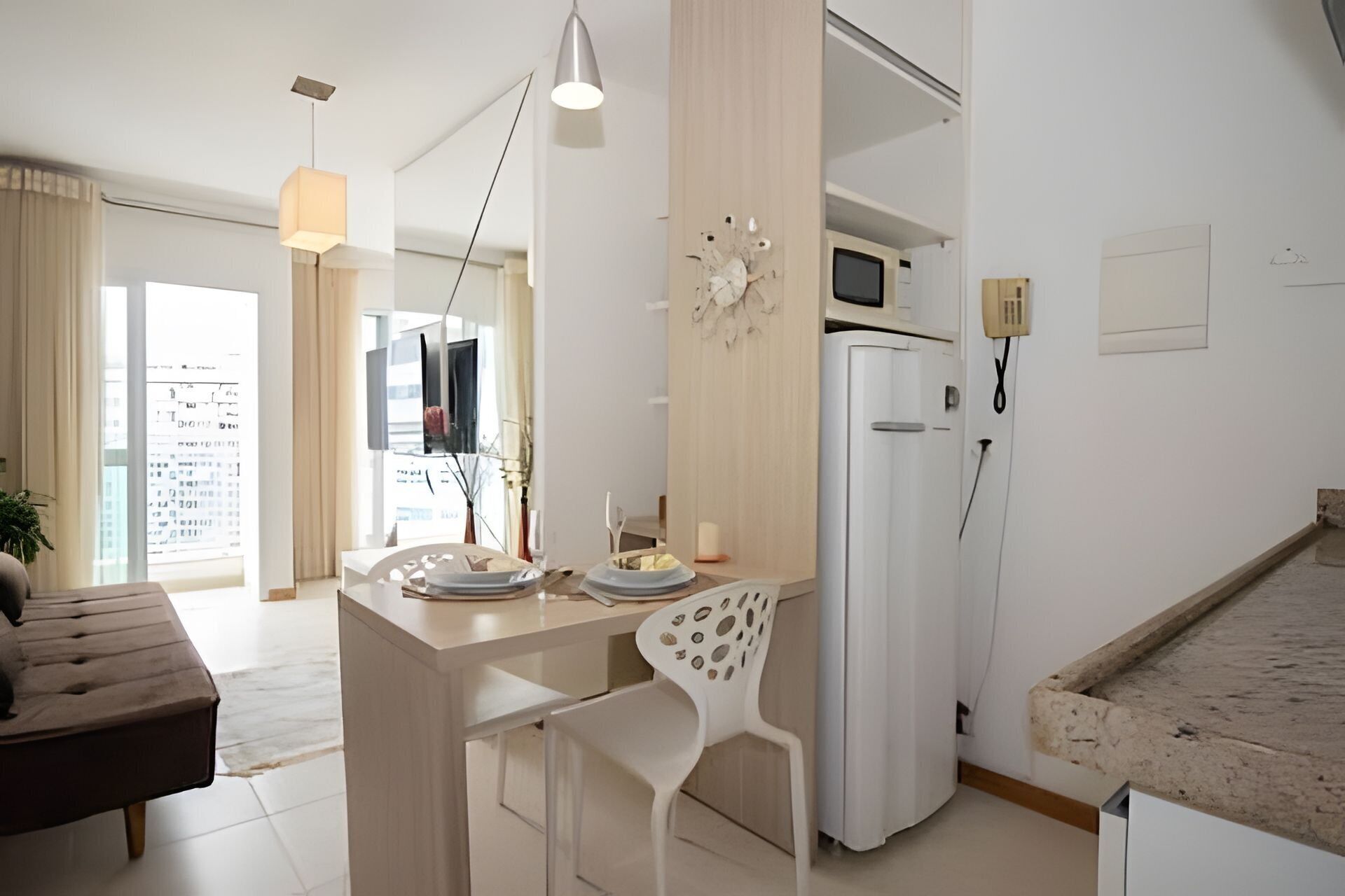 A modern kitchen with a dining area, a white refrigerator, and a microwave.