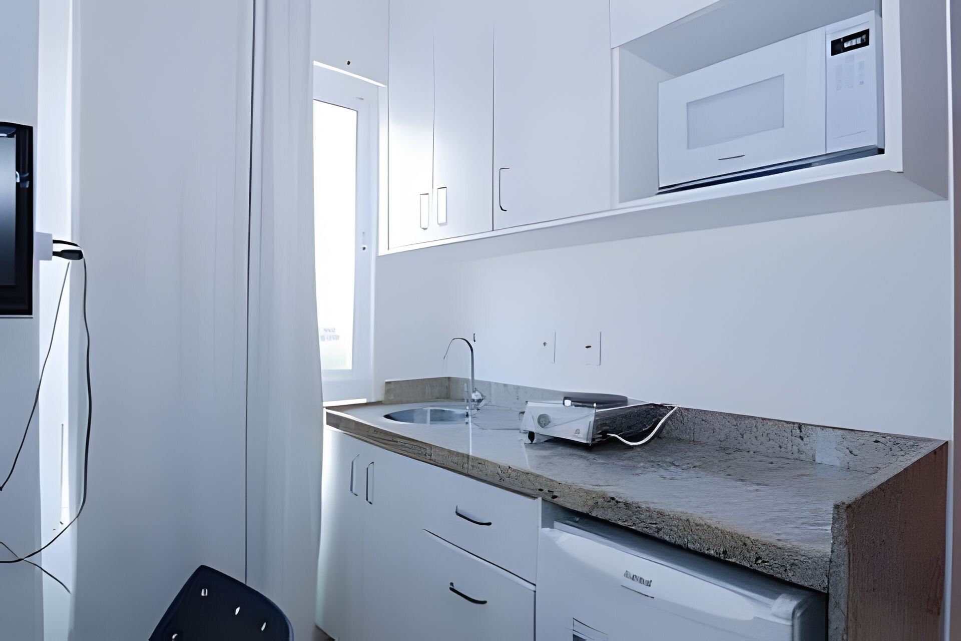 A modern kitchen with white cabinetry, a granite countertop, a built-in microwave, and a dishwasher.