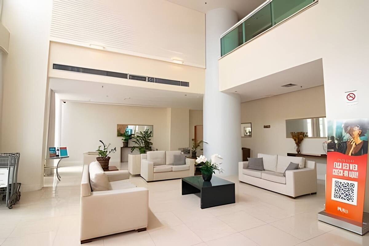 A spacious lobby with high ceilings, a central column, and two seating areas with sofas and a coffee table.