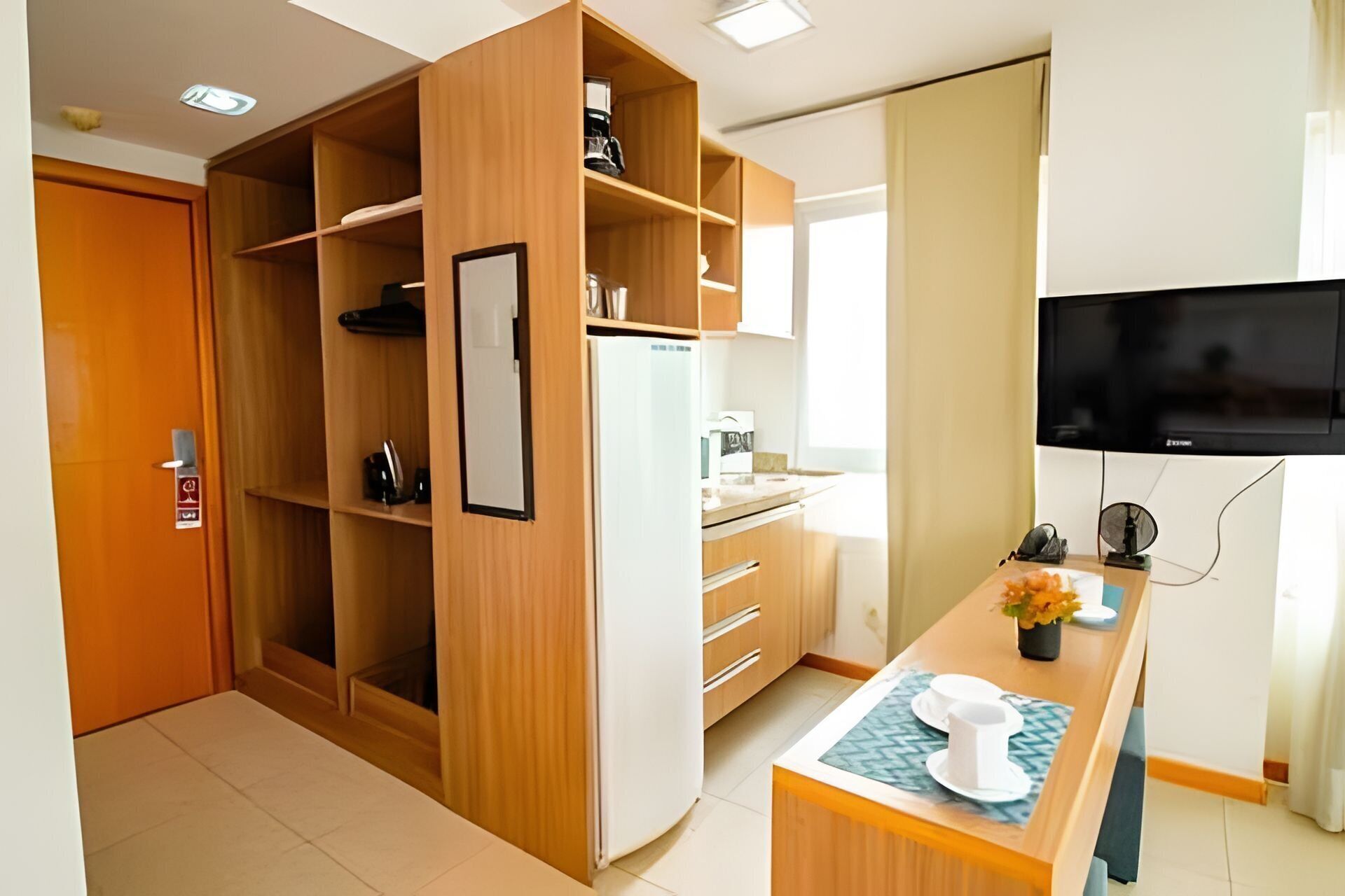 A modern kitchen with wooden cabinets, a built-in refrigerator, a microwave, and a dining area with a table set for two.
