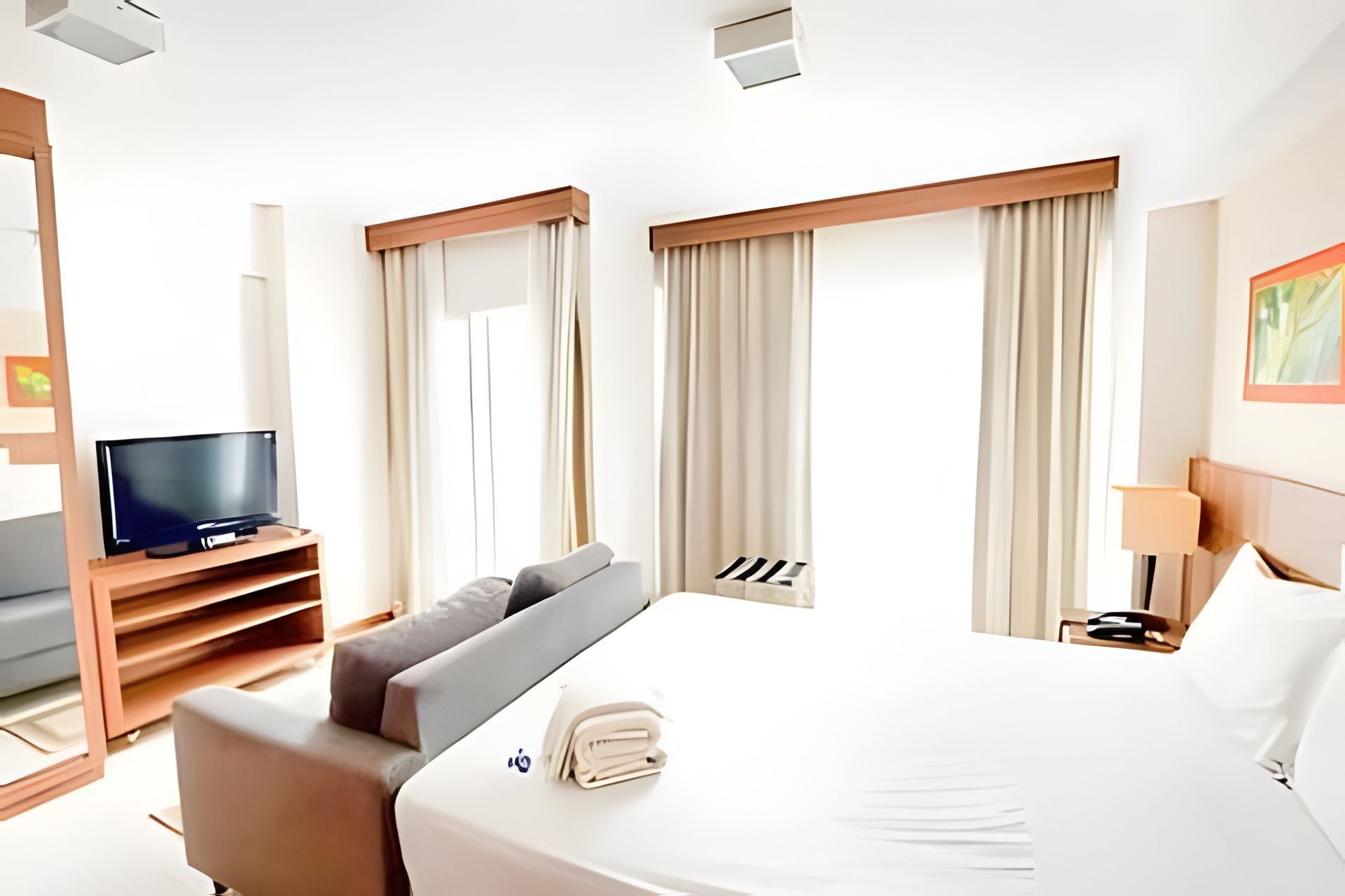 A hotel room with a bed, a TV, a desk, and a chair.