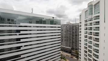 A modern high-rise building with a reflective glass facade, multiple balconies, and a clear view of the surrounding urban environment.