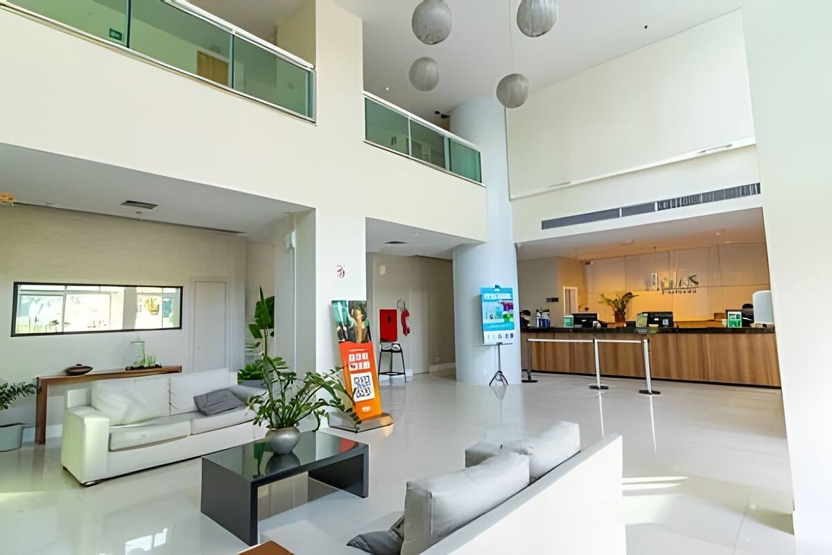 A spacious lobby with a reception desk, a sofa, a coffee table, and a plant.