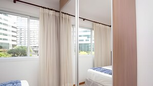 A hotel room with a bed, a window with curtains, and a view of buildings outside. - OZPED Flats Particulares Saint Moritz (Brasília)