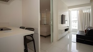 A modern, well-lit room with a dining table, chairs, a TV mounted on the wall, and a balcony with curtains. - OZPED Flats Particulares Saint Moritz (Brasília)