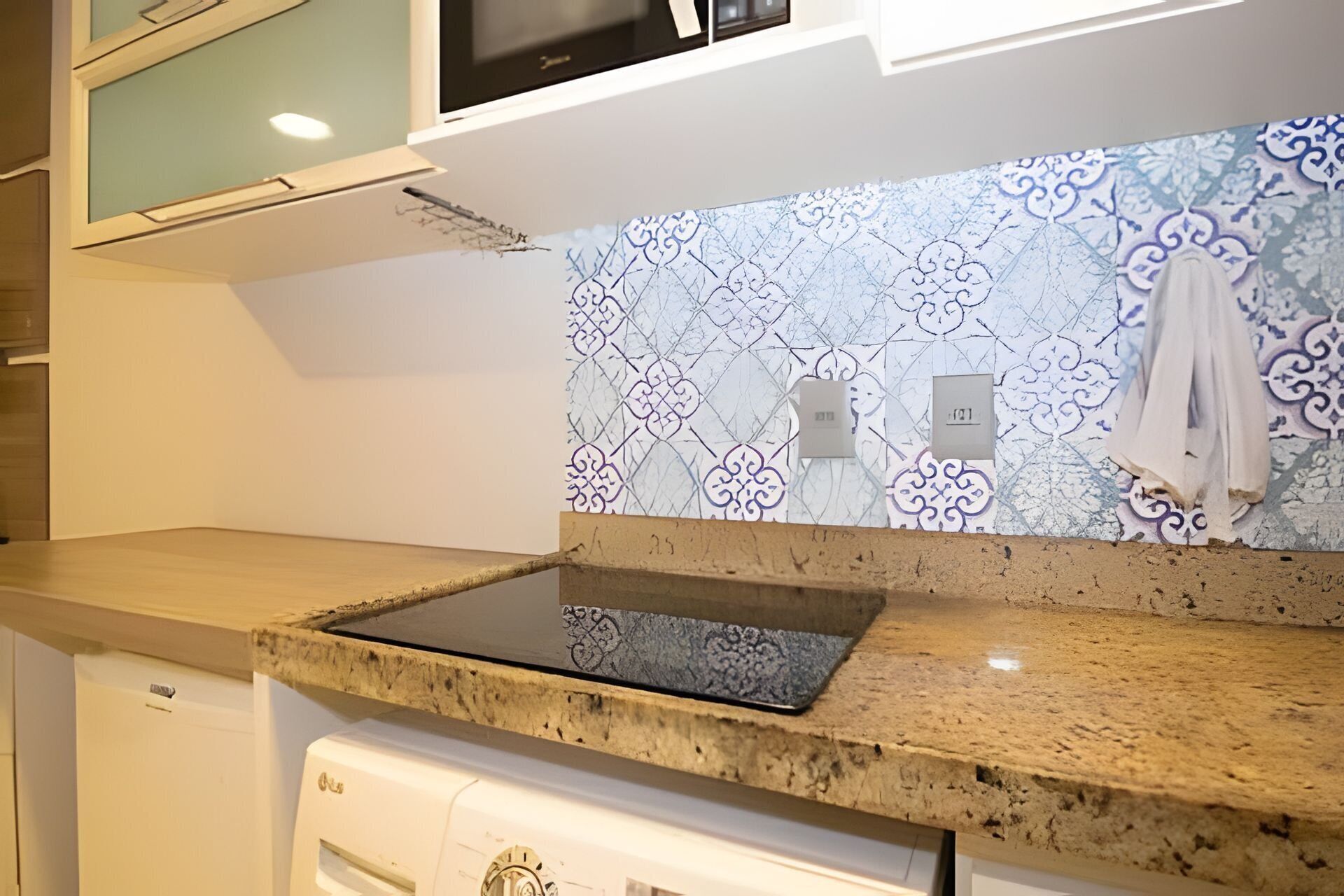 A kitchen with a granite countertop, a built-in oven, and a patterned backsplash.