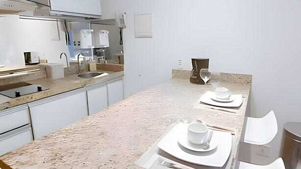 A modern kitchen with a marble countertop, stainless steel appliances, and a minimalist design. - OZPED Flats Particulares Saint Moritz (Brasília)