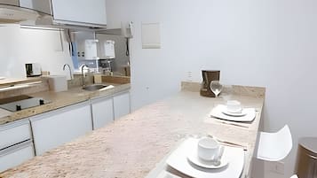 Een moderne keuken met een marmeren aanrecht, roestvrijstalen apparatuur en een minimalistisch ontwerp.