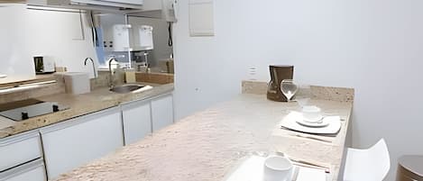 Una cocina moderna con encimera de mármol, electrodomésticos de acero inoxidable y un diseño minimalista.