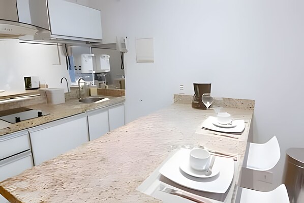 A modern kitchen with a marble countertop, stainless steel appliances, and a minimalist design.