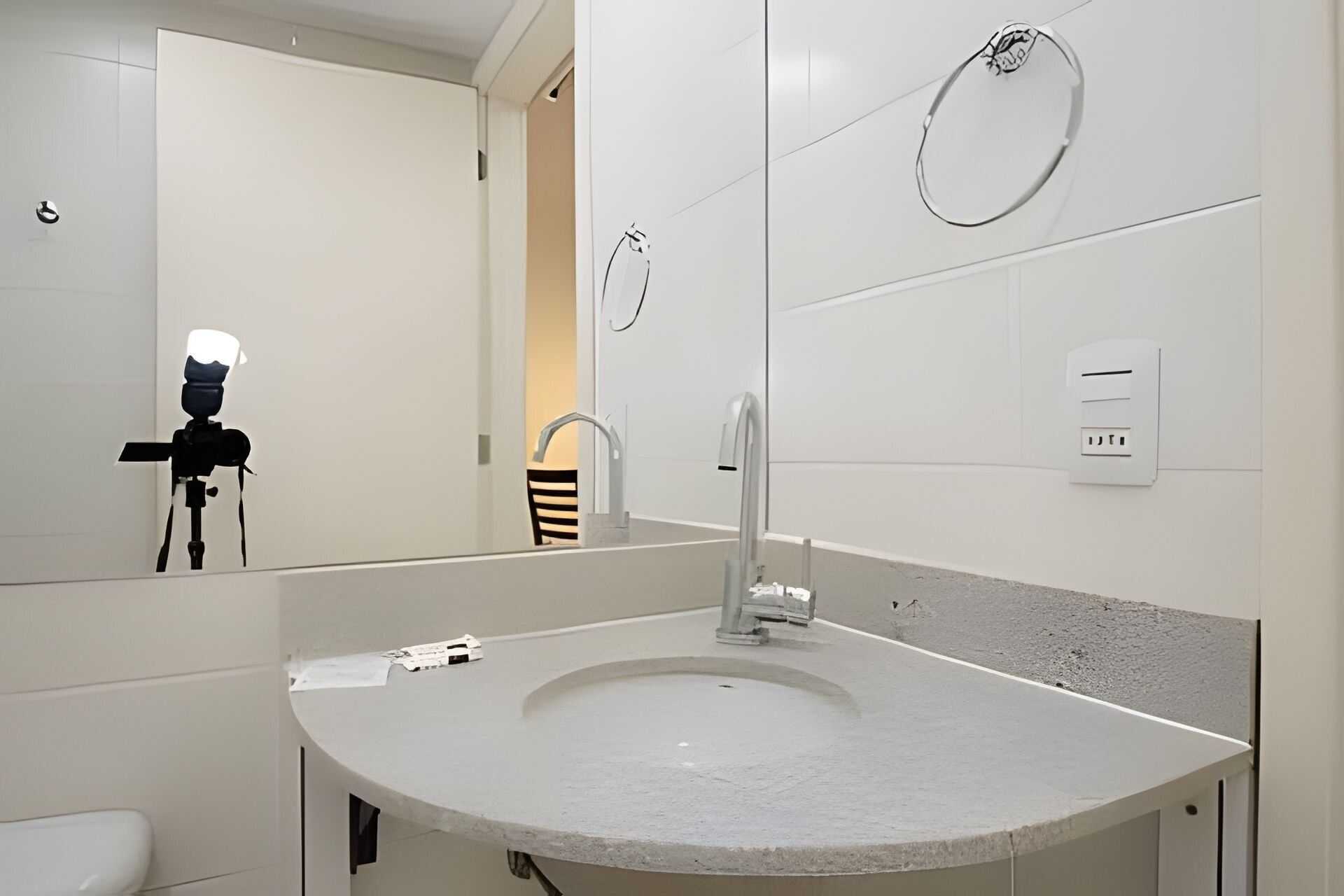 A modern bathroom with a large mirror, a sink, a towel rack, and a toilet.