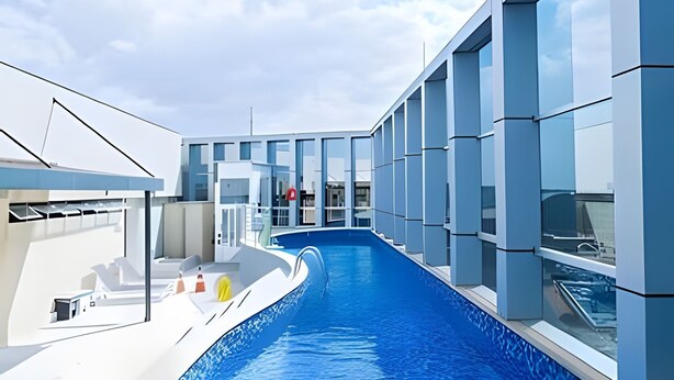 Un espace piscine moderne avec une eau d’un bleu limpide, de grandes fenêtres et un design architectural contemporain.