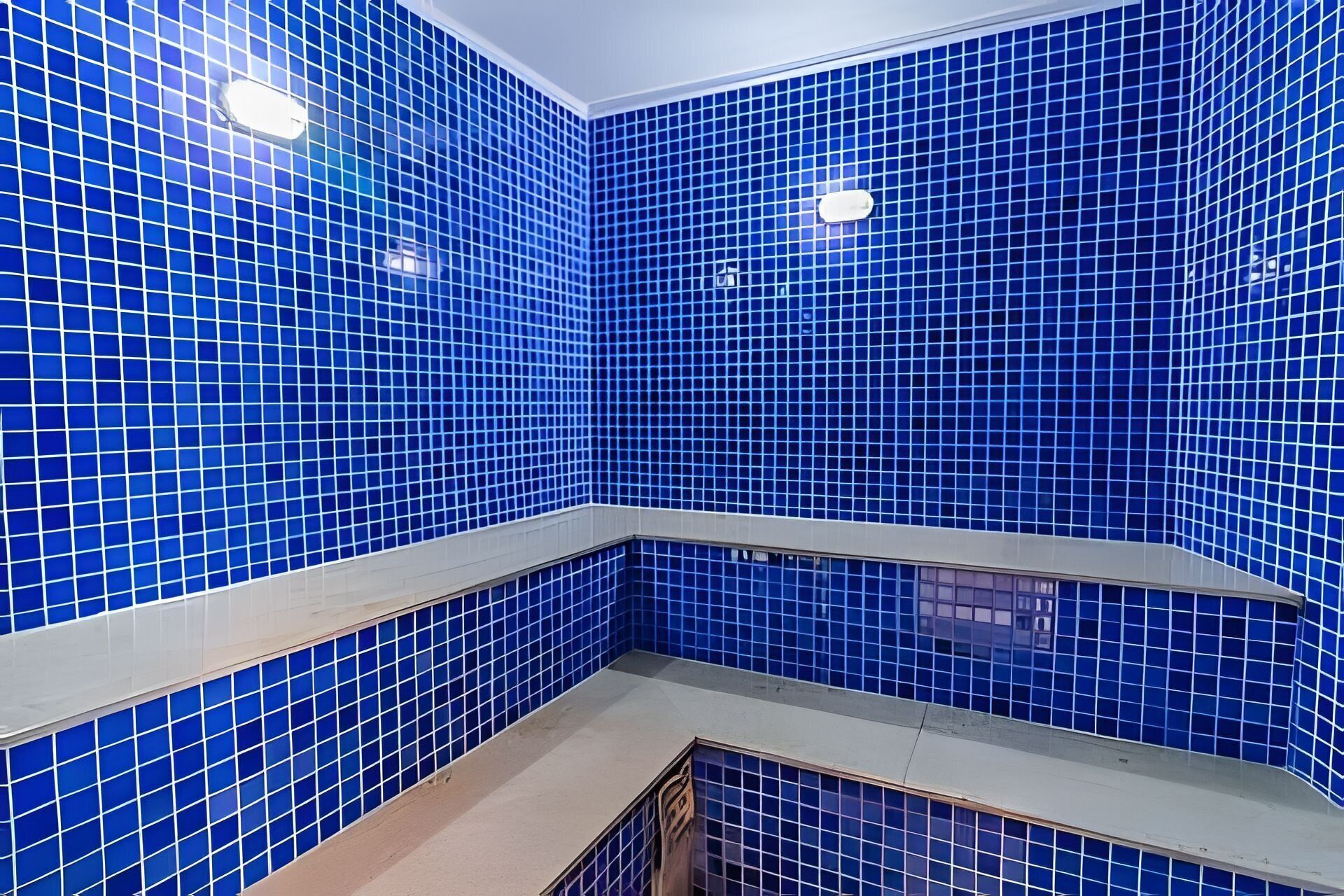 Une salle de bain avec des murs recouverts de carreaux bleus et un comptoir blanc.