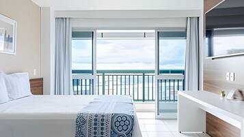 Une chambre d’hôtel avec un lit, une télévision, un bureau et un balcon offrant une vue.
