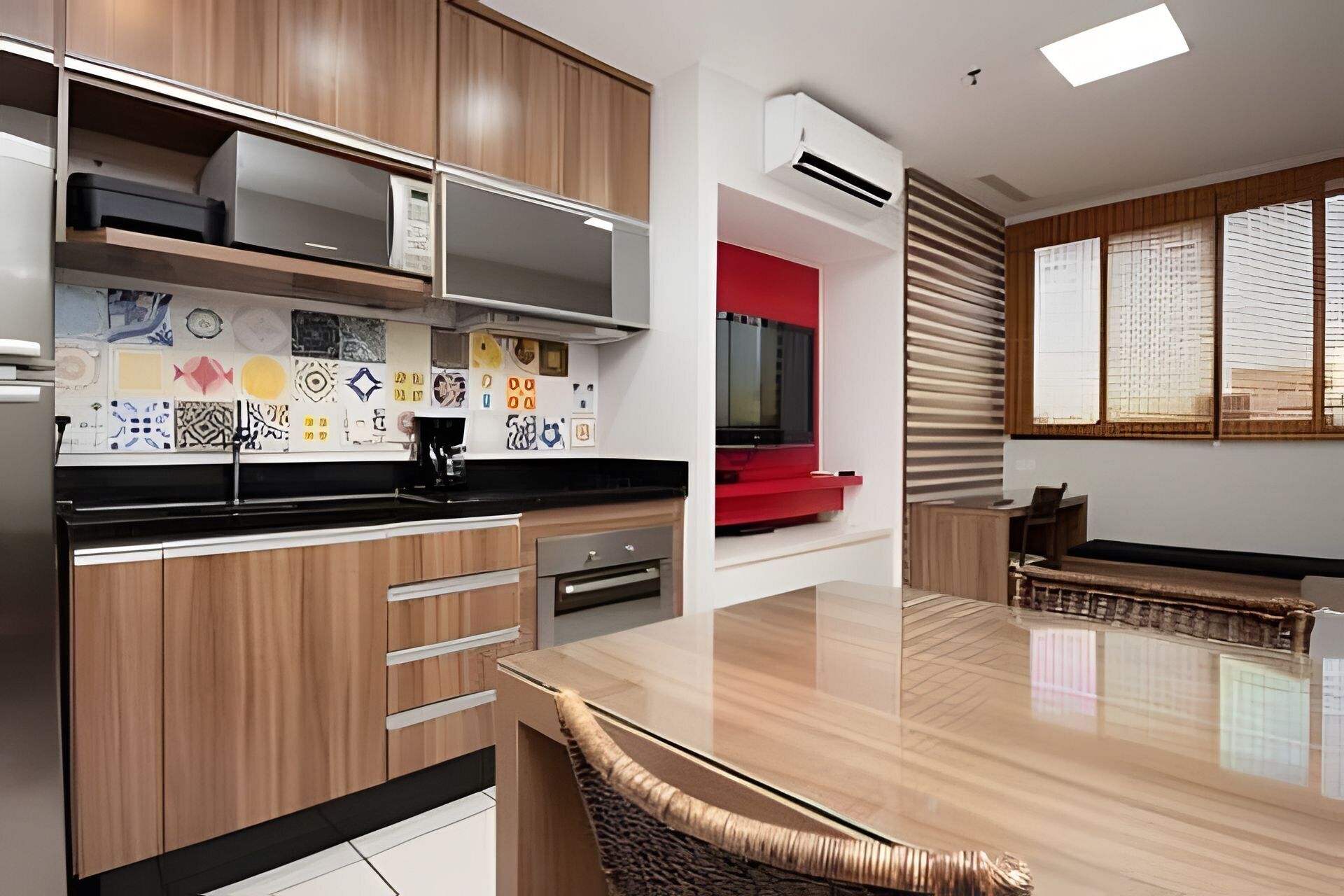 Une cuisine moderne avec des meubles en bois, un plan de travail noir et un mur d’accent rouge.