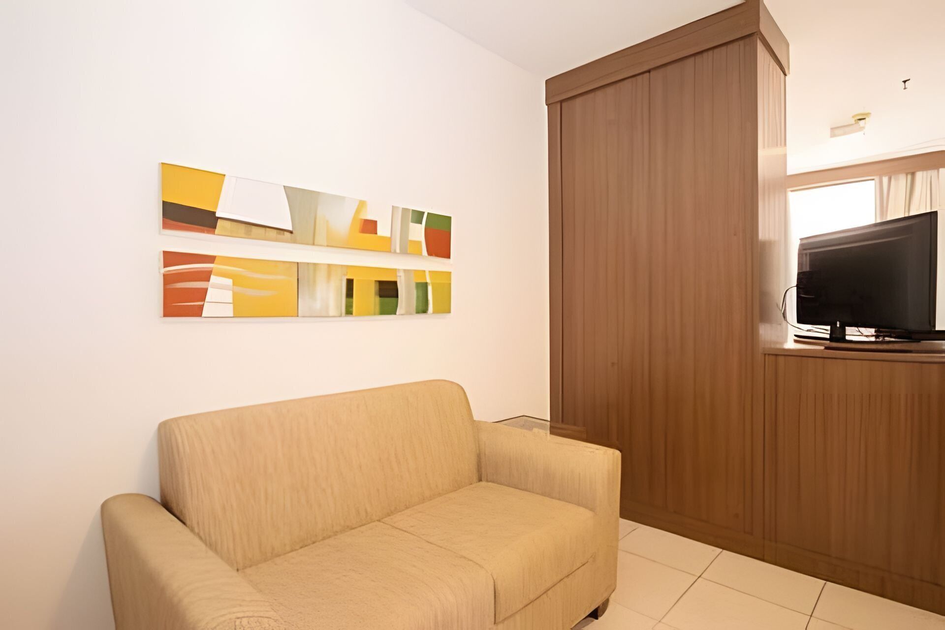 A living room with a sofa, a television, and a wooden cabinet.