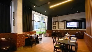 Un restaurant avec des banquettes, des tables et un écran de télévision.