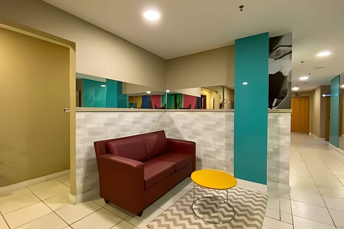 Un hall d’entrée moderne avec un canapé rouge, une table jaune et un tapis à motifs.