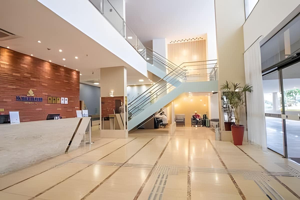 Un hall d’entrée moderne avec un comptoir d’accueil en bois, un escalier et une entrée en verre.