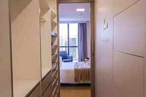 A hotel room with a bed, a desk, a chair, and a window with curtains.