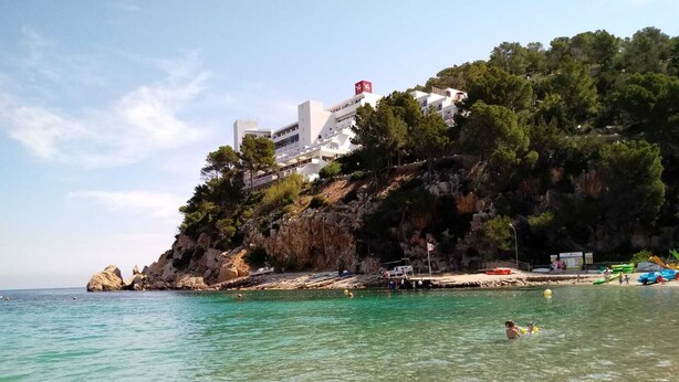 Ein Küstenhotel mit einer felsigen Klippe und klarem, türkisfarbenem Wasser.