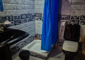 A bathroom with a black sink, white bathtub, and a black toilet. The walls are tiled with a mix of black and white patterns. - Nile sky hotel and suites (Cairo)